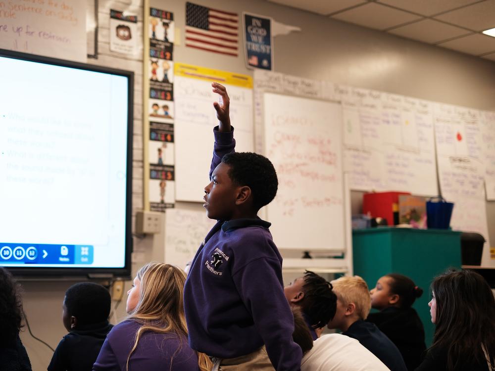 Second grader Ethan Williams raises his hand during whole-group reading instruction.