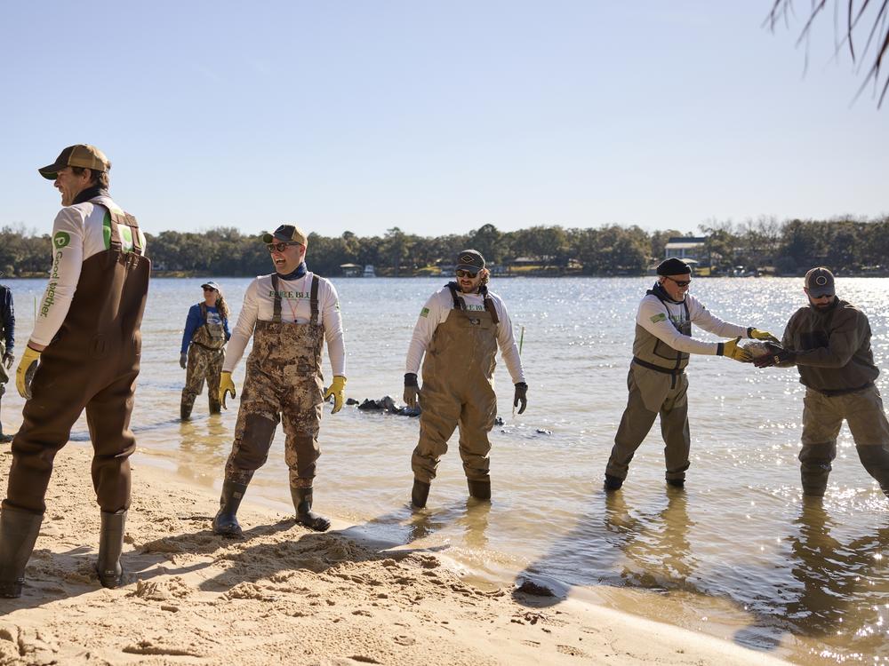 Veterans and volunteers with Force Blue use an assembly line to transport stones to build a rubble wall in Ft. Walton Beach, Fla.