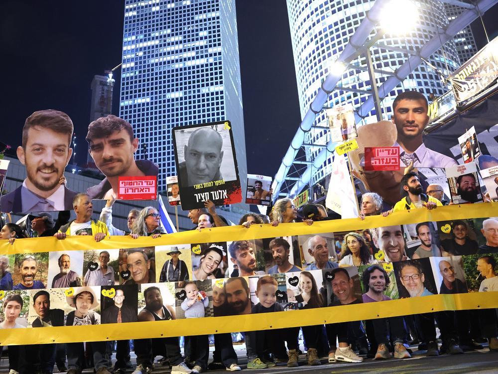 Friends and relatives of Israeli hostages held captive since the October 7, 2023 attacks by Palestinian militants in the Gaza Strip, stand behind a banner bearing their portraits during a demonstration calling for action to secure their release in front of the Israeli Defense Ministry in Tel Aviv on Tuesday.