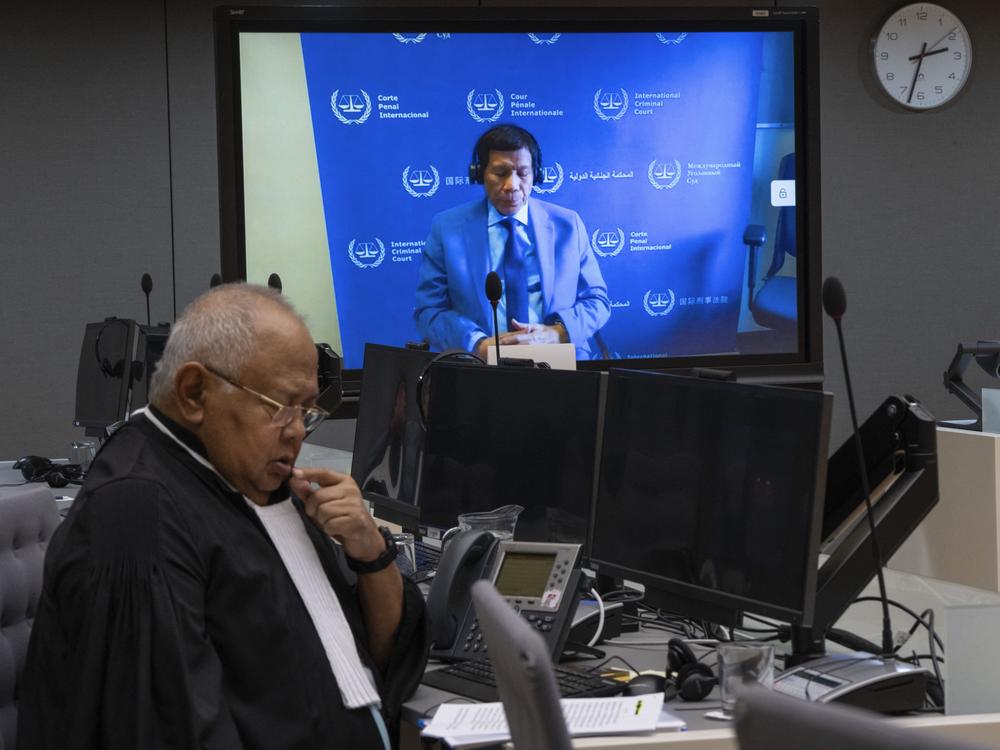 Former Philippine President Rodrigo Duterte is seen on a screen with his lawyer Salvador Medialdea (left) in the courtroom during his first appearance before the International Criminal Court on charge of crimes against humanity over his deadly crackdown on narcotics, in The Hague on March 14.