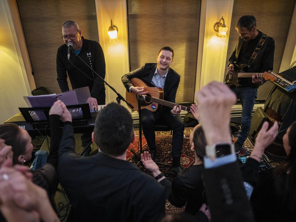 Jens-Frederik Nielsen, center, chairman of Demokraatit Party, plays guitar as he reacts during the election party at Demokraatit by cafe Killut in Nuuk, early Wednesday, March 12, 2025.