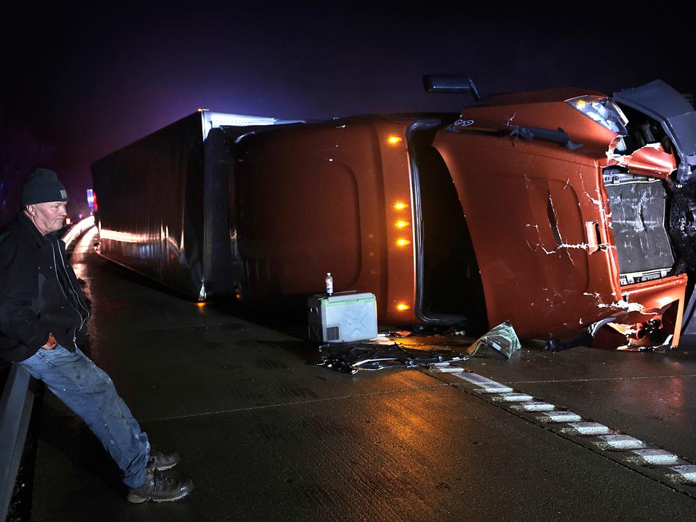 Mark Nelson, of Wis., waits with his tractor-trailer after it overturned during high winds and a possible tornado on Interstate 44 westbound at Villa Ridge, Mo.,  on Friday.