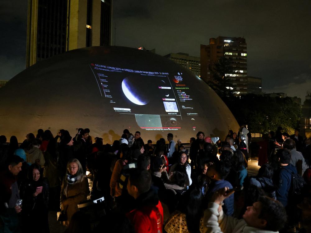 People gather on the roof of the district planetarium to watch a lunar eclipse in Bogota, Colombia on Friday.