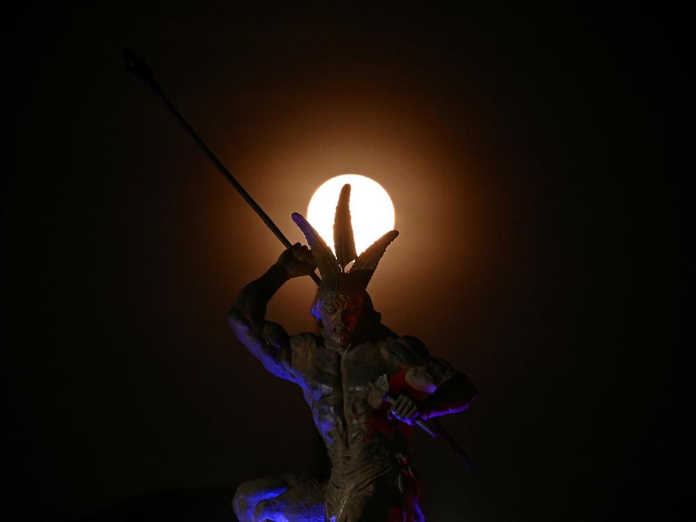 A full moon is seen behind a statue after a lunar eclipse in Caracas, Venezuela on Friday.