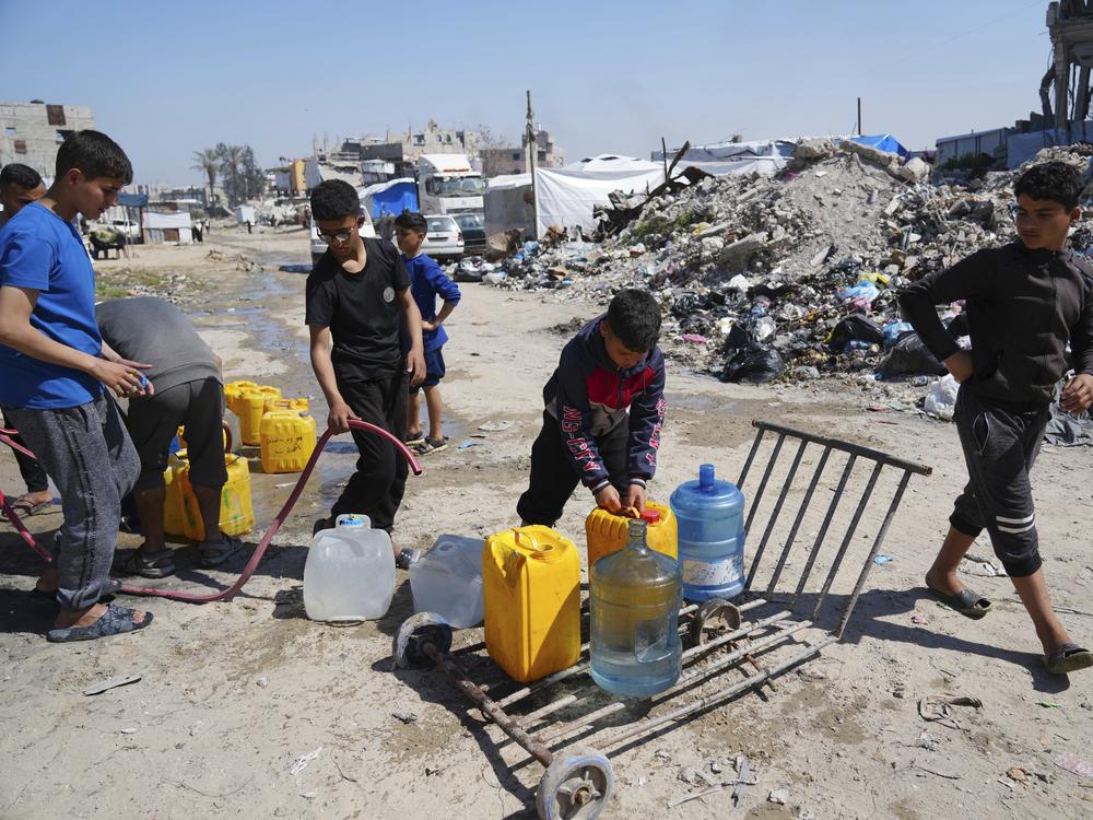 Young Palestinians fill cans with water in Jabaliya, northern Gaza Strip, on Sunday. Arab negotiators are trying to broker a ceasefire deal that would avert a return to fighting in Gaza and begin serious negotiations toward a formal end of the war, since the breakdown of the Israel-Hamas ceasefire deal at the beginning of the month.