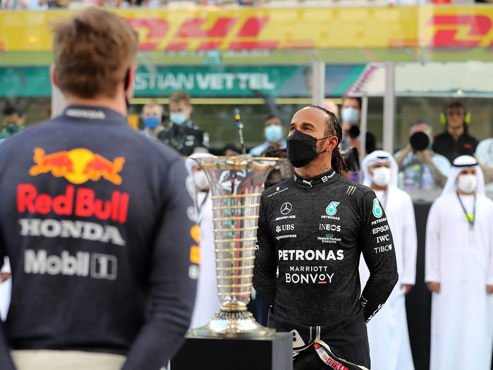 Championship contenders Max Verstappen of Netherlands and Red Bull Racing and Lewis Hamilton of Great Britain and Mercedes GP stand in front of the F1 World Drivers Championship Trophy on the grid before the F1 Grand Prix of Abu Dhabi on December 12, 2021 in United Arab Emirates.