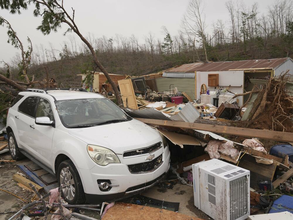 A vehicle sits in front of a damaged home and debris from a severe storm Saturday, March 15, 2025, in Wayne County, Mo.