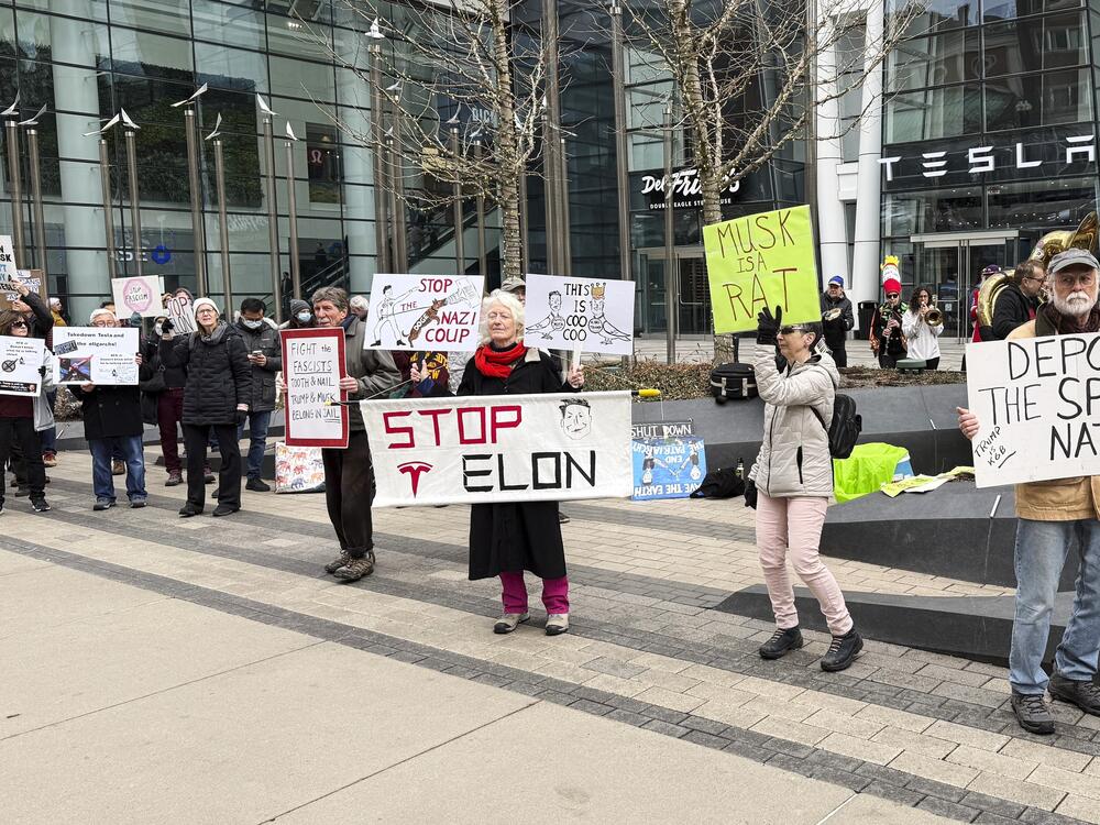 Protesters rally outside a Tesla store in Boston on March 1 against the company's CEO, Elon Musk, who is leading an effort to cut government jobs on behalf of President Trump.