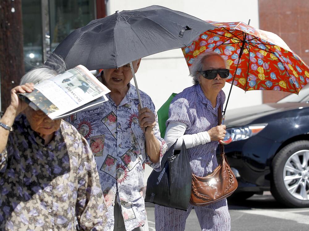 Older people in Los Angeles' Chinatown neighborhood shade themselves from the sun. Exposure to heat can change the way people's genes work, potentially leading to long-term health impacts. Climate change is making heat waves more intense and last longer in many parts of the U.S.