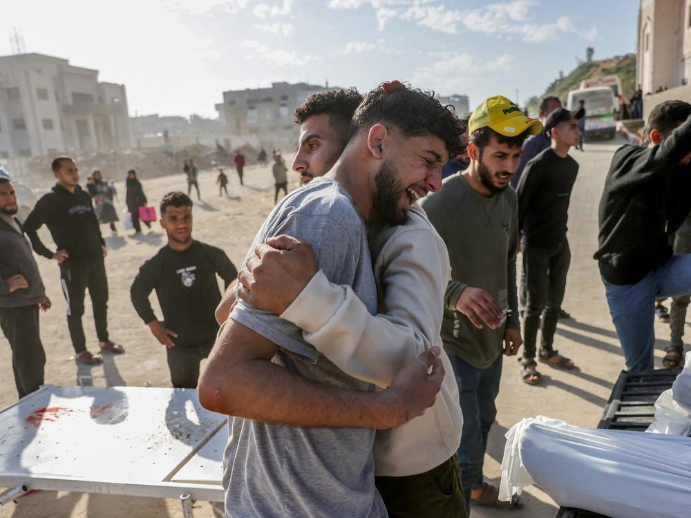 A Palestinian man is comforted as he weeps next to a truck carrying the bodies of the victims of Israeli overnight airstrikes before transporting them for burial on Tuesday. Israeli airstrikes killed more than 400 people and injured hundreds more on one of the most intense strikes in Gaza since the war began in 2023.