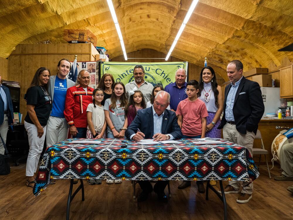 Then-Gov. John Bel Edwards signs HB 261, establishing École Pointe-au-Chien, in June 2022 at the Pointe-au-Chien Indian Tribe building in front of tribal members, officials, children and other stakeholders.<br>
