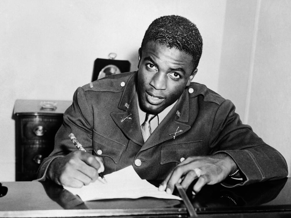 Jackie Robinson, shown here in military uniform signing a contract with a farm team for the Brooklyn Dodgers, is among the veterans whose Department of Defense webpages were removed — and then restored — as part of the Trump administration's scrubbing of references to DEI material.