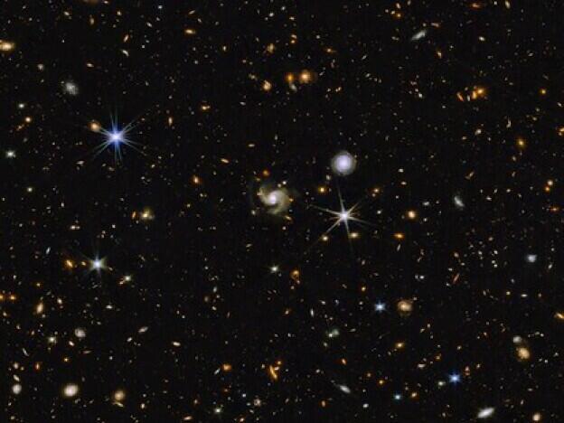 This multi-wavelength image from NASA shows a universe full of galaxies that are various shapes, colors and sizes. Most are small while a handful are somewhat larger. A few stars are also scattered across the image.