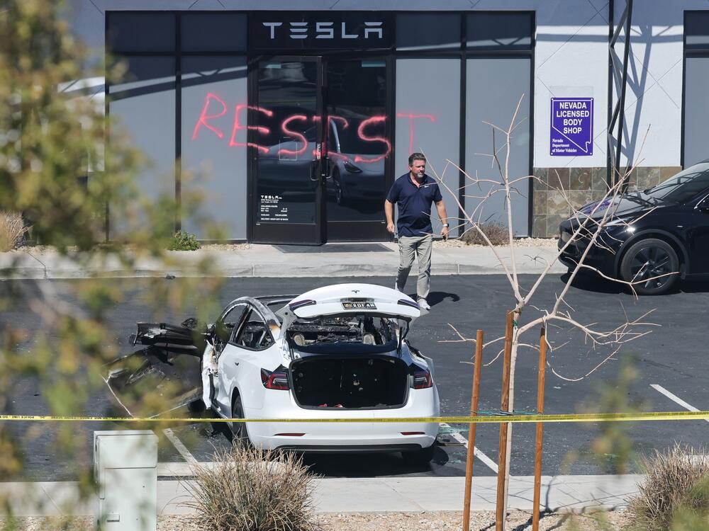 An investigator looks over the scene at a Tesla Collision Center after a person used incendiary devices to set several vehicles on fire on Tuesday in Las Vegas. The Las Vegas Metropolitan Police Department said that five Teslas were damaged and believe that the suspect fired three rounds from a firearm at the vehicles and spray painted the word 