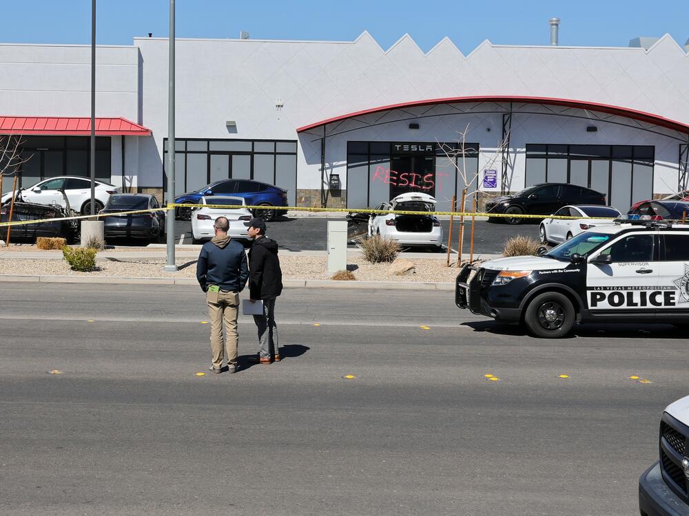 Investigators look over the scene at a Tesla Collision Center after a person set several vehicles on fire on Tuesday in Las Vegas.