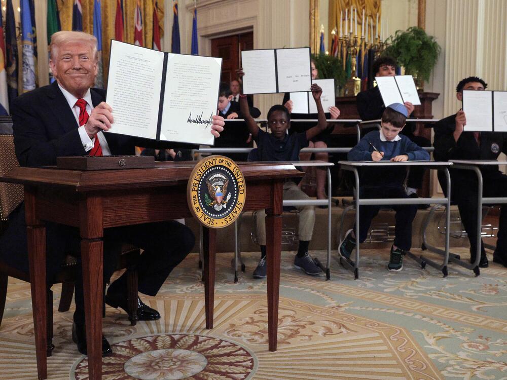 President Donald Trump signs an executive order to reduce the size and scope of the Education Department alongside school children signing their own versions, during a ceremony in the East Room of the White House on March 20.