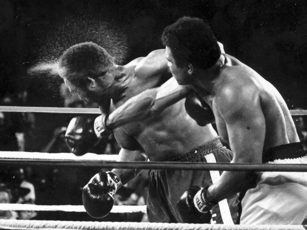 Perspiration flies from the head of George Foreman as he takes a right from challenger Muhammad Ali in the seventh round in the match dubbed Rumble in the Jungle in Kinshasa, Zaire, Oct. 30, 1974.