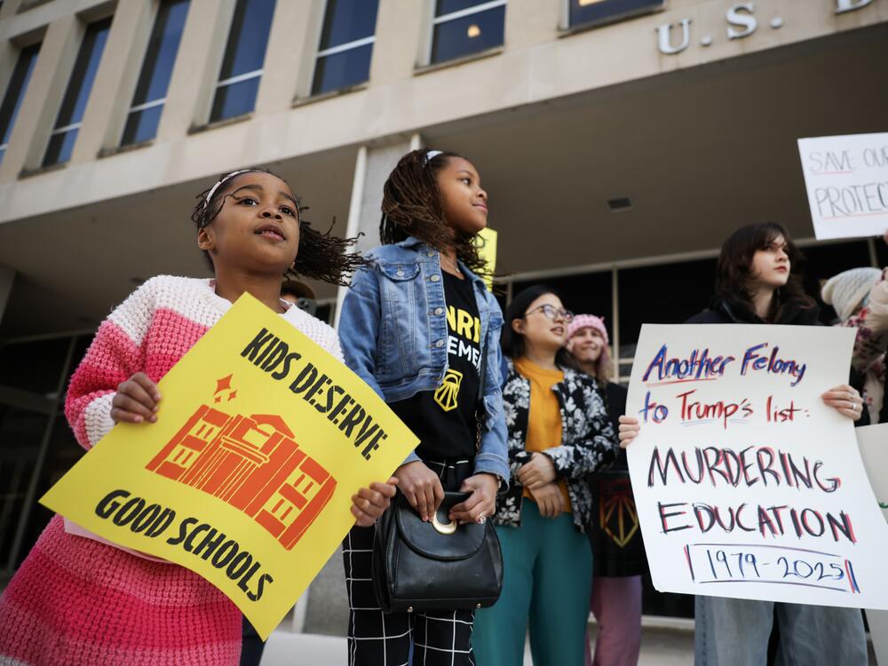 Naomi, 7 (Left), and Makena, 9 (Center) hold signs and chant during a rally in front of the Department of Education to protest budget cuts.