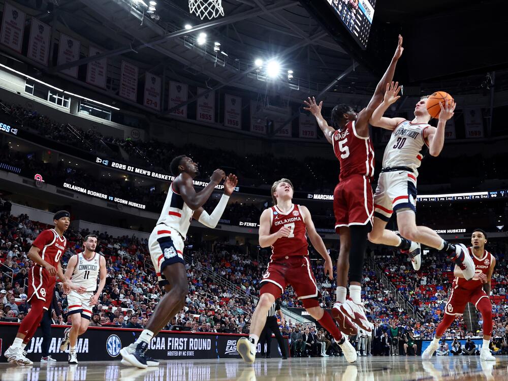 Liam McNeeley #30 of the Connecticut Huskies shoots the ball while defended by Mohamed Wague #5 of the Oklahoma Sooners during the first half in the first round of the NCAA Men's Basketball Tournament at Lenovo Center on March 21, 2025 in Raleigh, North Carolina.