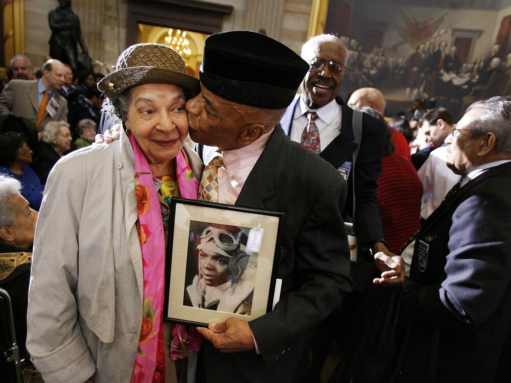 Holding a photograph of himself as a 19-year-old pilot, Tuskegee Airman Lt. Col. John Mulzac of Brooklyn, N.Y., kisses his wife Beatrice Mulzac after a ceremony honoring the World War II air group with a Congressional Gold Medal in 2007 in Washington, D.C.