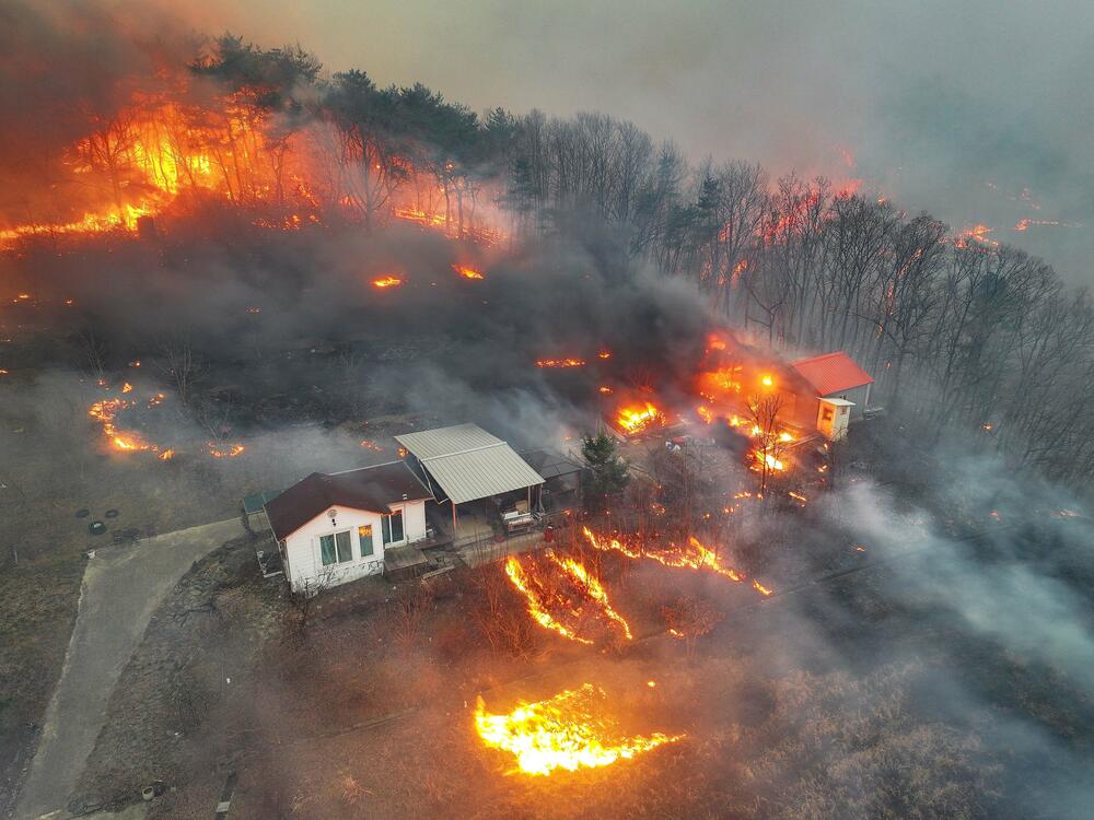 Houses burn in a village after being engulfed by a wildfire fueled by strong winds in Uiseong, South Korea on Monday.