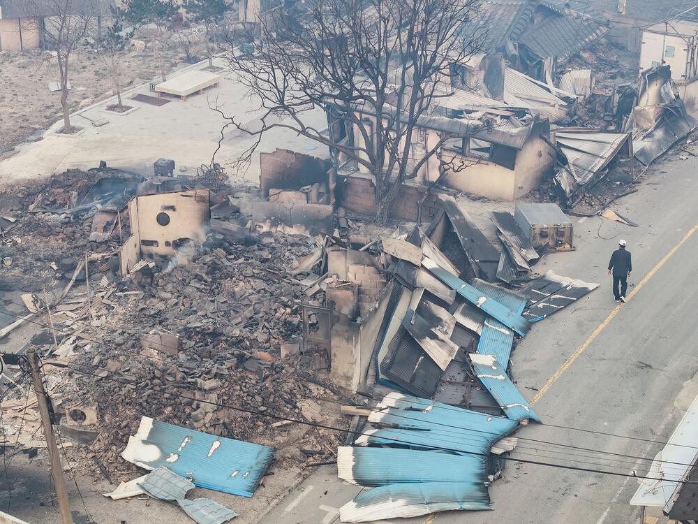 A man walks near a burnt-out house in a damaged village in Yeongyang, South Korea on Wednesday.