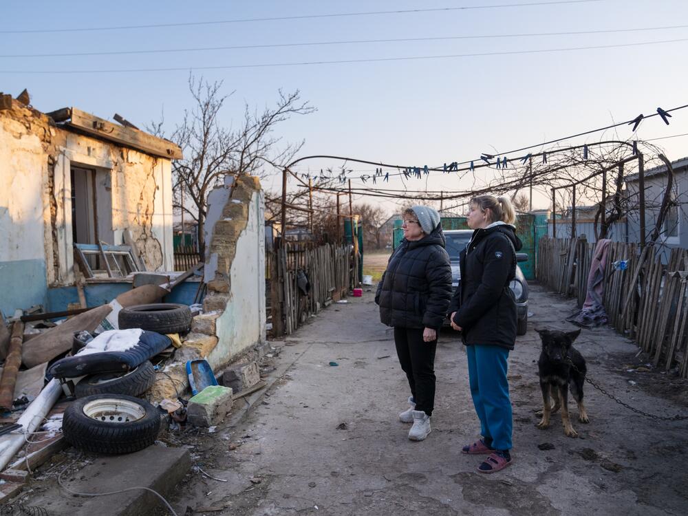 Oksana Hnedko (left) talks with Zeleny Hai resident Nina Kolesnik, 32, about the remnants of her old home on one side of her property. A temporary unit where she lives now is on the other side.