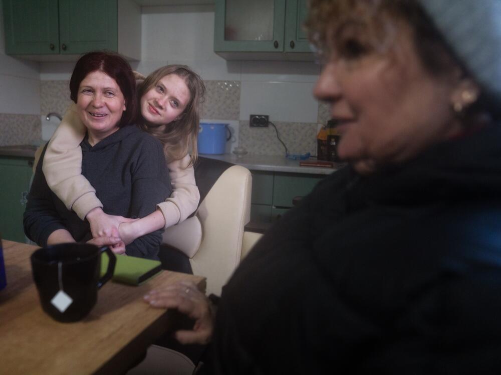 Nadia Huscha, 37, (left) and her daughter Anna, 14, talk with Oksana Hnedko in their home that was repaired in Zelenyi Hai. With most of the town's buildings already fixed, Hnedko and Huscha can actually dream of a return to normal. They reminisce about the annual village celebration, the last of which they had in 2021. And they talk about their hopes of having another celebration again someday.