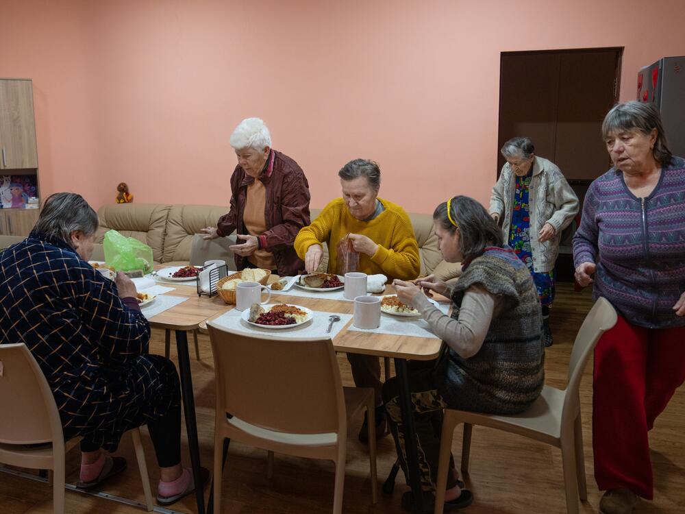 Internally displaced people staying at the ARTAK shelter in Zaporizhzhia gather for dinner. Anastasia found a sense of community by volunteering at ARTAK, where she helps other displaced people, including seniors and the disabled. It's like family, she says.