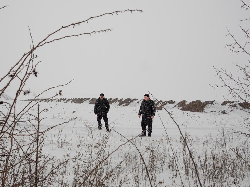 Konstyantyn Hordienko (left) and his father Viktor Hordienko stand on a road that leads to their land in Staryi Saltiv. Viktor sometimes goes just to check on the land, tallying the damage. 