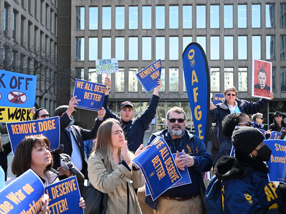 Protesters hold signs in solidarity with the American Federation of Government Employees at a March 4 rally in support of federal workers at the Office of Personnel Management in Washington, D.C.