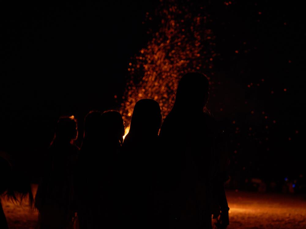 Girls watch a bonfire during an Apache Sunrise Dance.