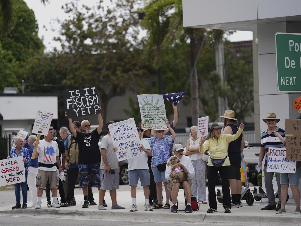 People protest outside a Tesla dealership on Saturday in Miami.