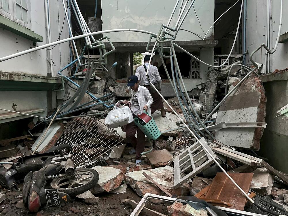 A resident carries belongings over debris next to a damaged building in Naypyidaw on March 28, 2025, after an earthquake in central Myanmar.