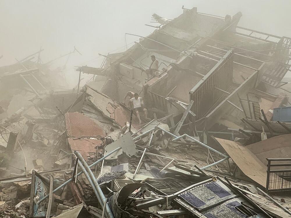 People inspect the debris of a collapsed building in Mandalay on March 28, 2025, after an earthquake.