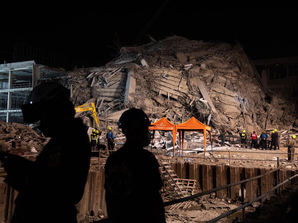 Rescue workers seen working at a collapsed building after an earthquake.