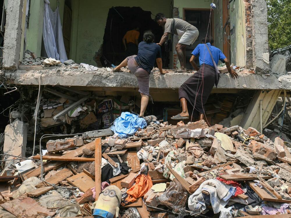 People climb into a damaged building as they look for survivors in Mandalay on March 29, 2025.