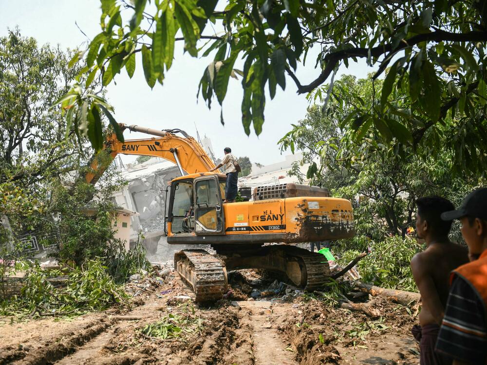 Heavy construction equipment is used to dig through the rubble as people look for survivors in a damaged building in Mandalay on March 29, 2025.