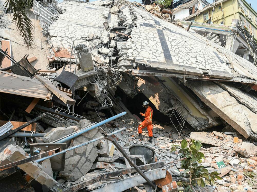 A rescue worker stands on rubble as teams attempt to free trapped residents at the destroyed Sky Villa Condominium development in Mandalay on March 29, 2025.