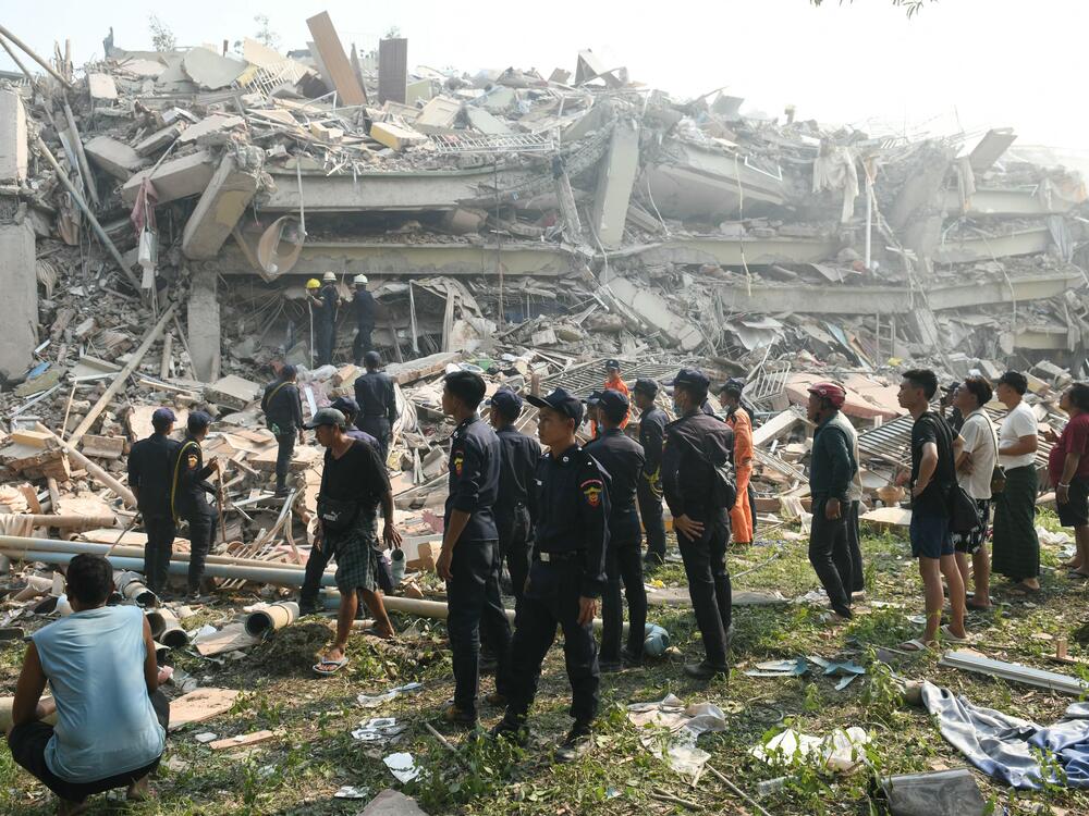 People watch as rescuers search for survivors trapped in the collapsed Sky Villa Condominium building in Mandalay on March 29, 2025, a day after an earthquake struck central Myanmar.