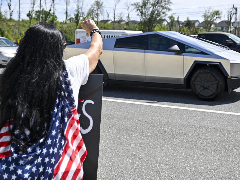 A Tesla cybertruck drives by as demonstrators rally against Tesla CEO Elon Musk outside a Tesla Store in Clermont, Fla., on Saturday.