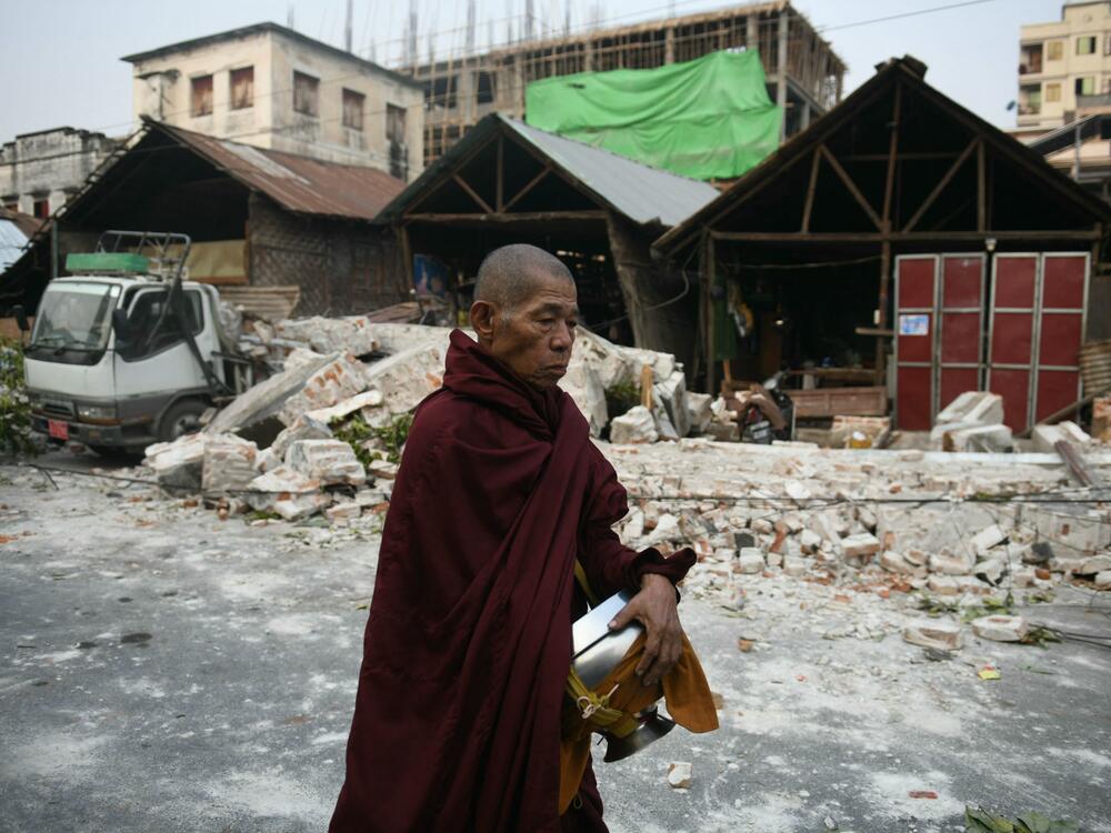 A monk walks past damaged houses in Mandalay on March 30, 2025.