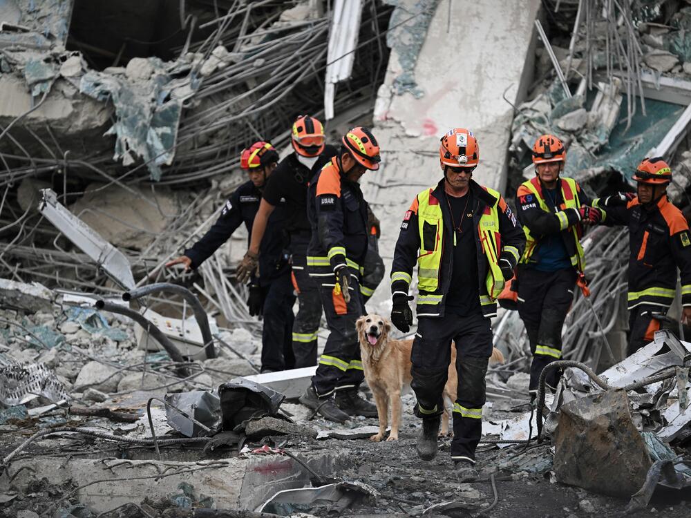 K-9 units search for missing persons at the site of an under-construction building collapse in Bangkok on March 30, 2025.