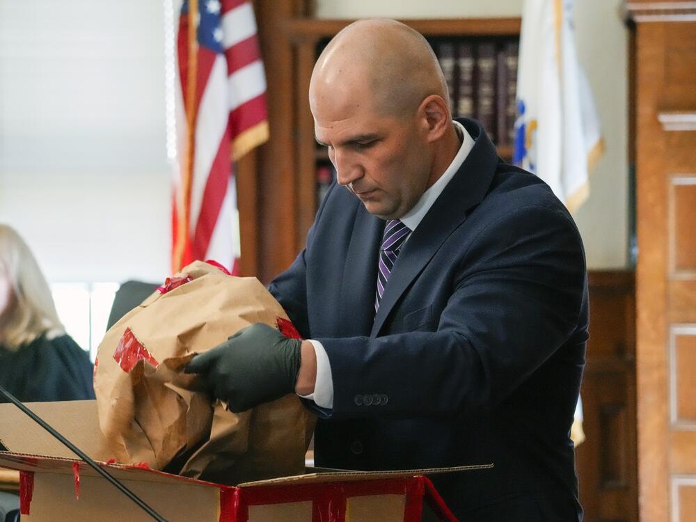 Michael Proctor, then a Massachusetts State Police trooper, opens an evidence box to show the jury a broken taillight while testifying in June 2024.