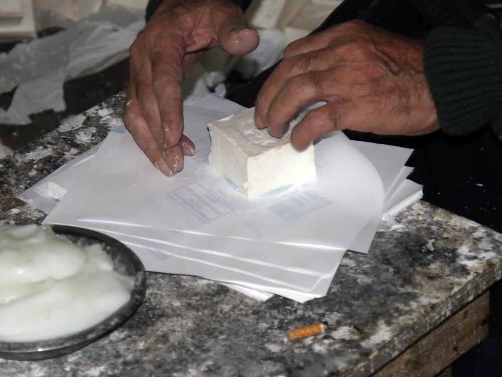A worker wraps a soap bar by hand in the company's signature white paper packaging.