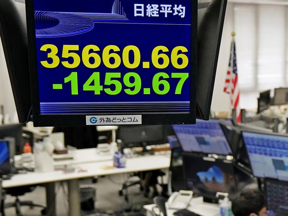 A currency trader works under an electronic stock board at a foreign currency trading firm in Tokyo Monday, March 31, 2025.