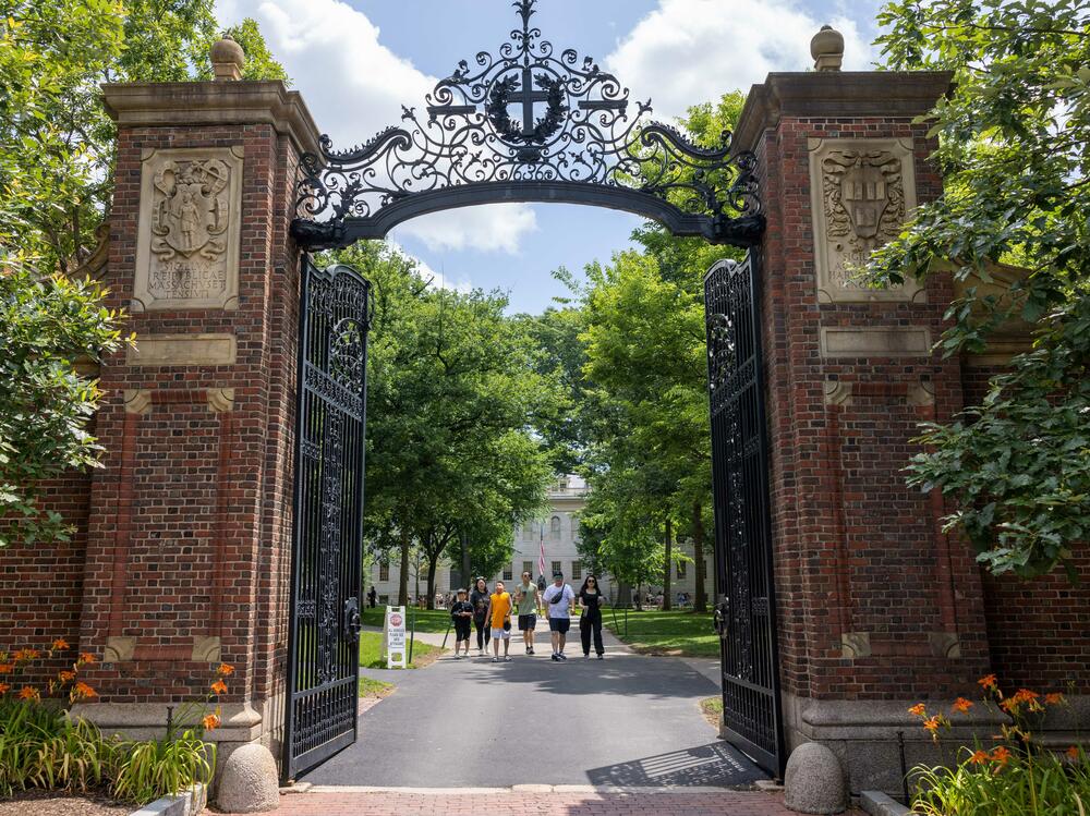 People walk through the gate on Harvard Yard at the Harvard University campus in Cambridge, Mass.
