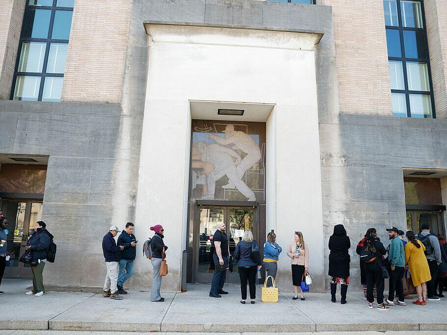 Employees of the Department of Health and Human Services stand in line to enter the Mary E. Switzer Memorial Building on April 01, 2025 in Washington, DC. Widespread layoffs began Tuesday across the agency.