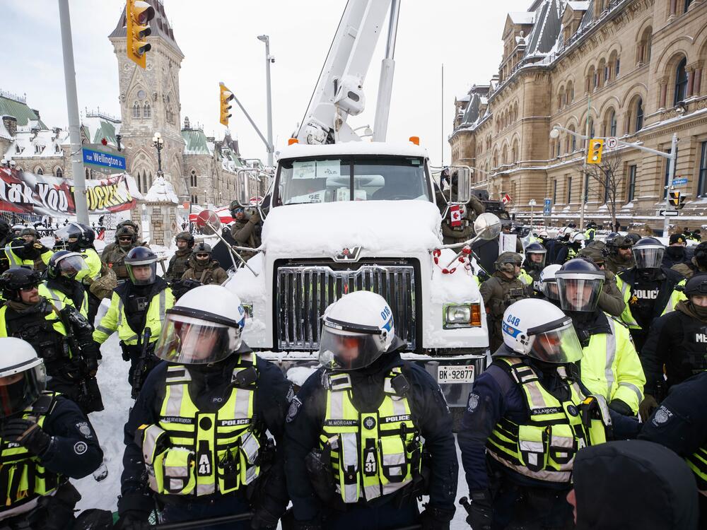 Police hang off a truck as authorities work to end a protest against COVID-19 measures in Ottawa on Feb. 19, 2022.