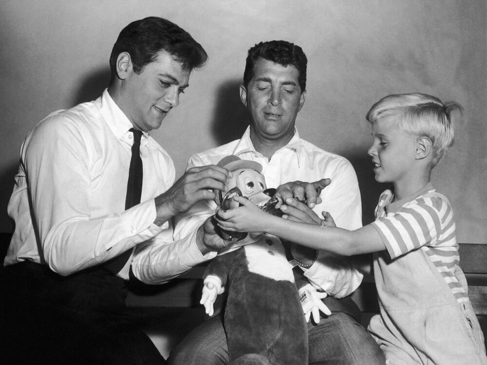 Jay North, young star of the new <em>Dennis the Menace</em> series, right, attempts to handcuff Dean Martin, center, as they play with a stuffed toy with Tony Curtis on Sept. 15, 1959.